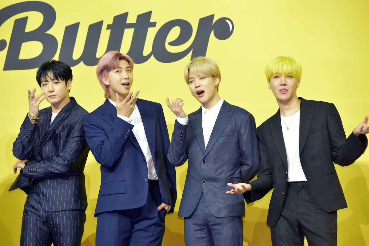 Jungkook, RM, Jimin, and J-Hope of BTS pose in suits side by side in front of a yellow background that says "Butter"