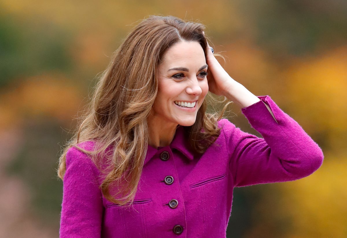 Catherine, Duchess of Cambridge waves in a purple coat