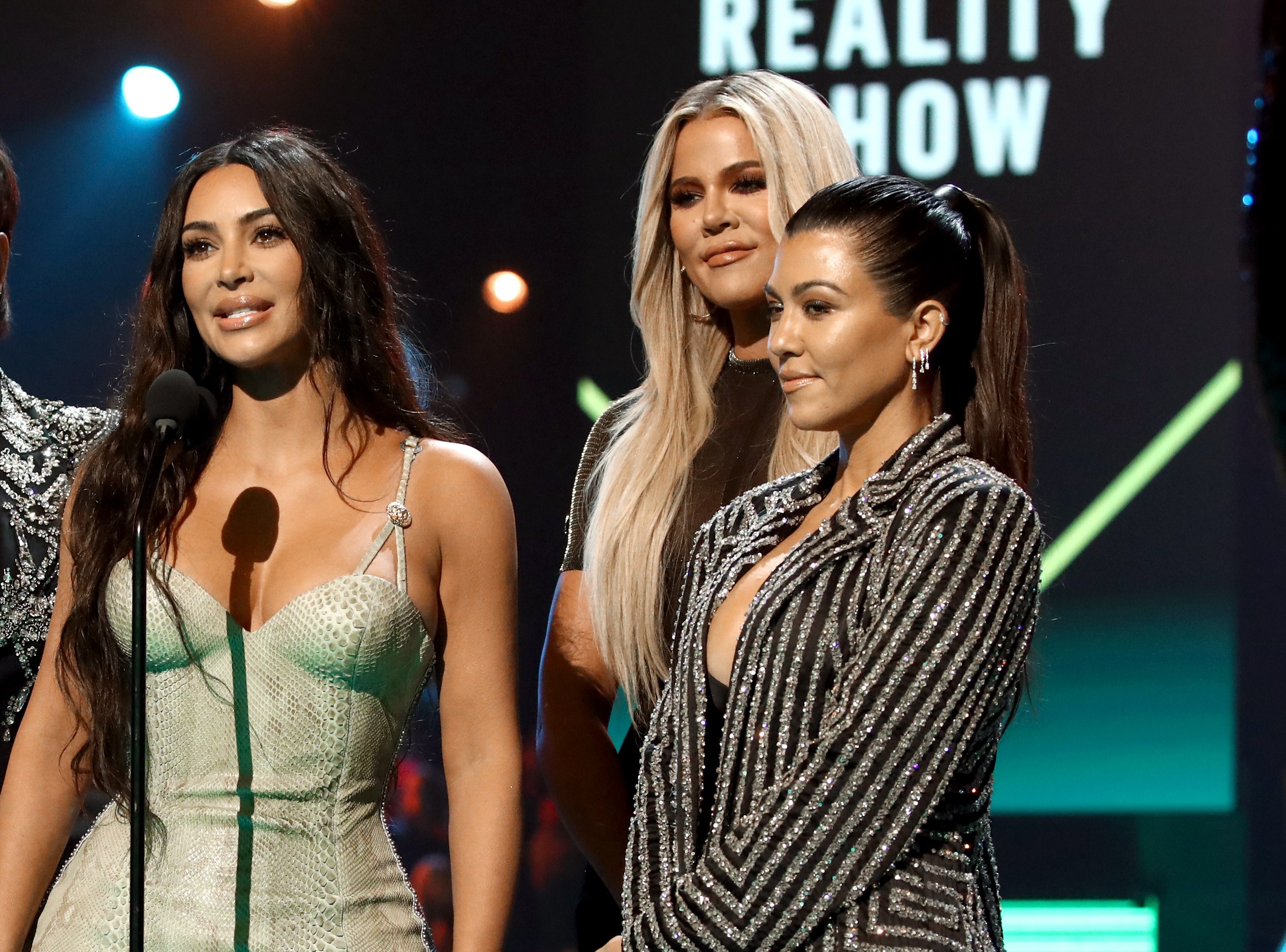 Kim Kardashian, Khloé Kardashian, and Kourtney Kardashian on stage accepting the 2019 E! People's Choice Awards