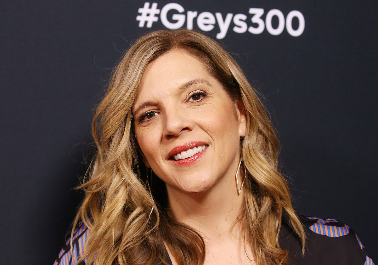 Krista Vernoff smiling in front of a #Greys300 sign