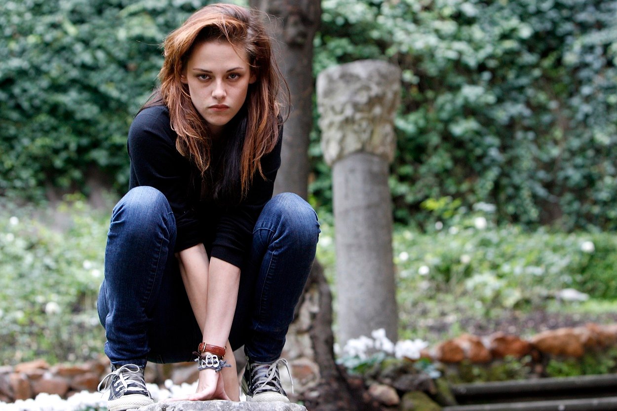 Twilight star Kristen Stewart as Bella Swan crouches in a long sleeve t-shirt and blue jeans for cast photos