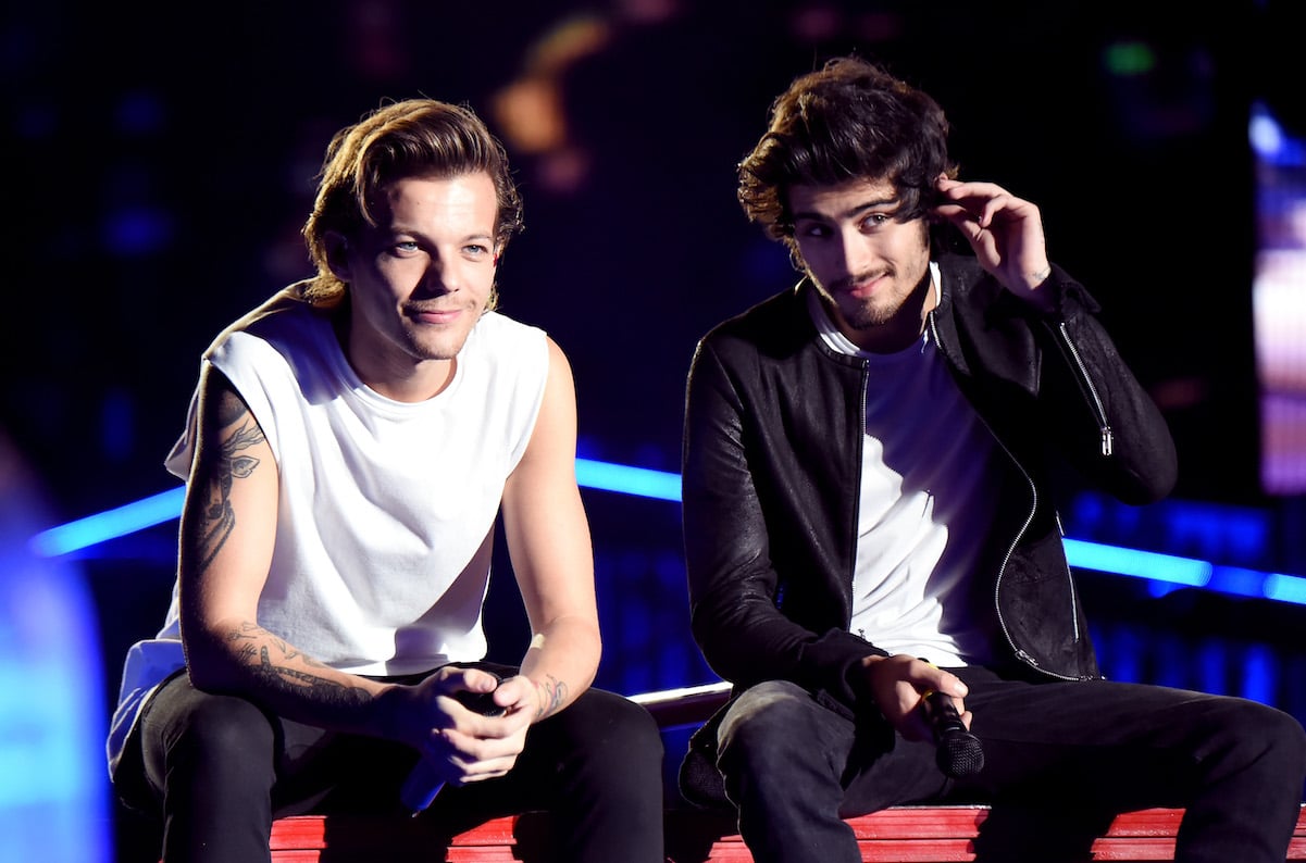 Louis Tomlinson and Zayn Malik sit down on stage during One Direction tour