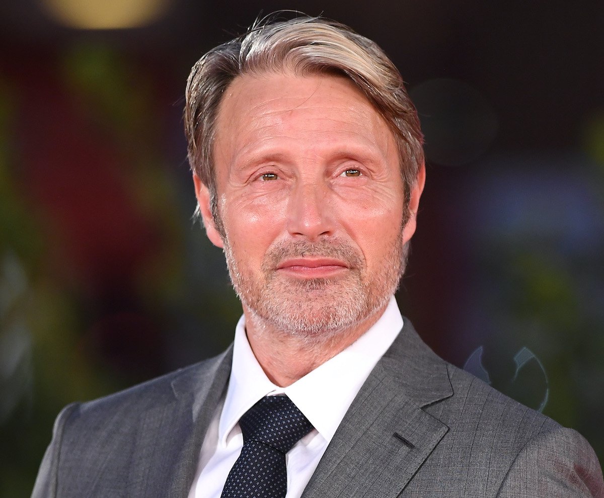 Mads Mikkelsen in a grey suit and navy blue tie