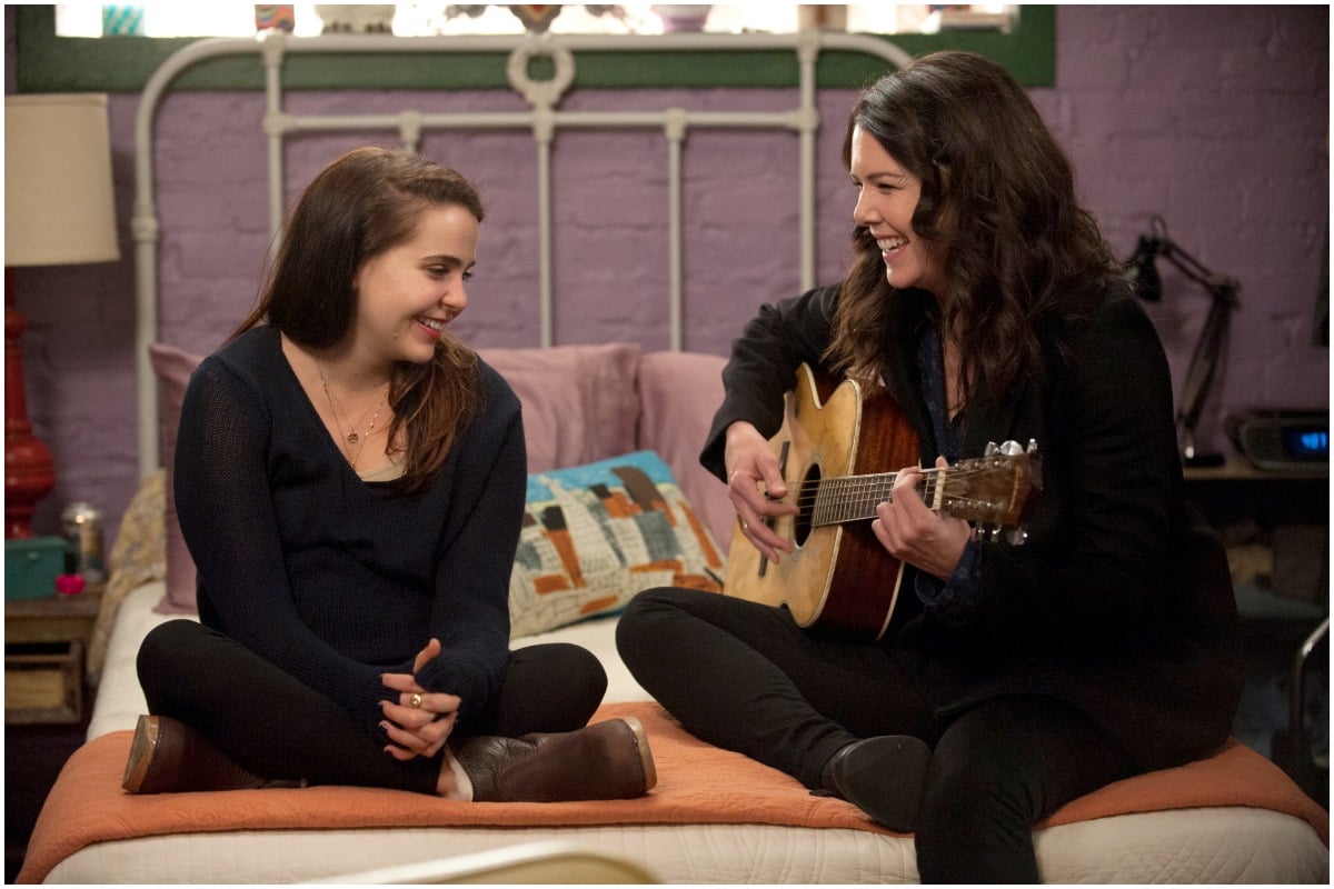 Mae Whitman and Lauren Graham sitting on a bed while smiling as Amber Holt and Sarah Braverman on 'Parenthood'