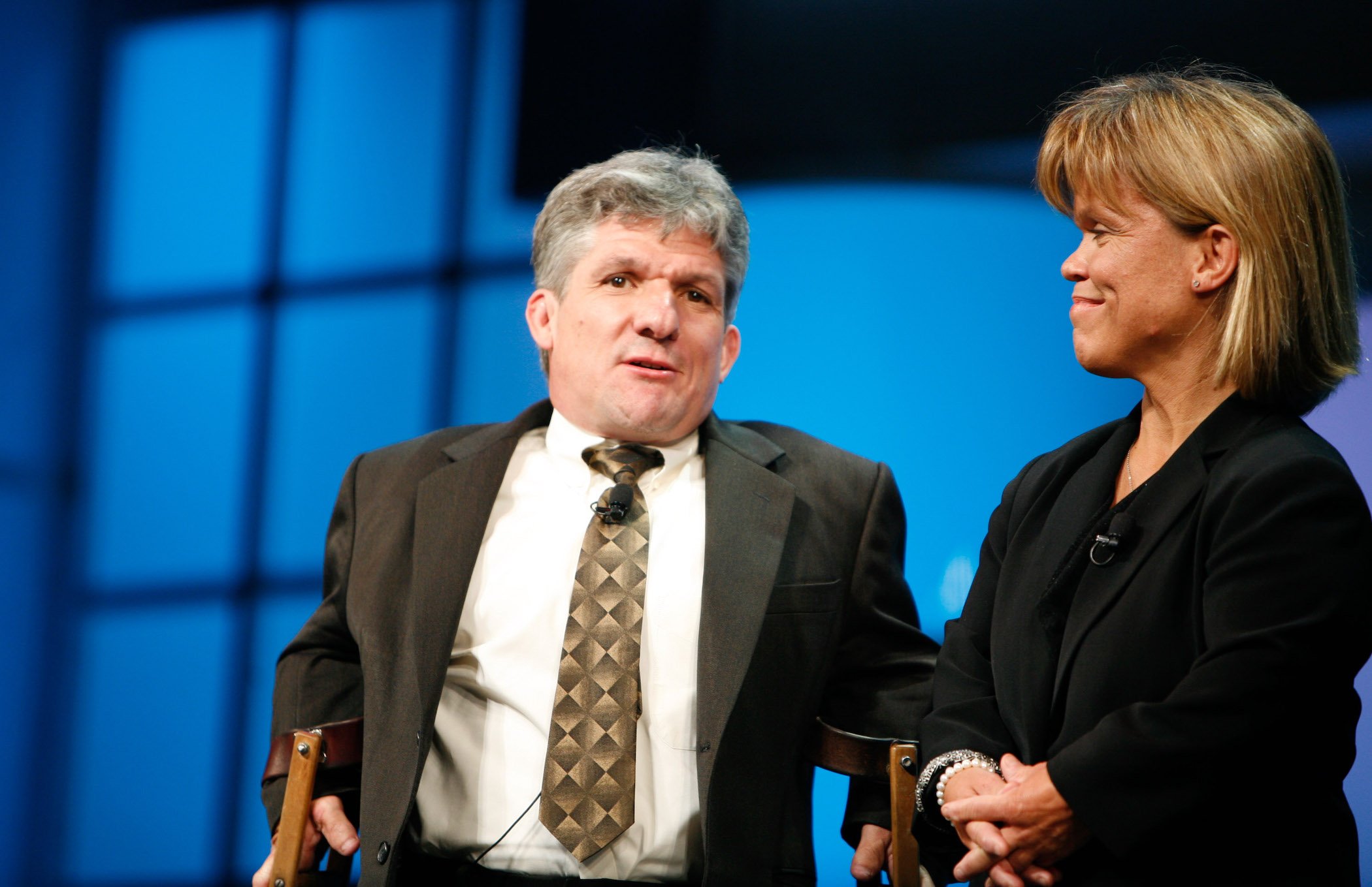 Matt and Amy Roloff, parents of Zach, Jeremy, Molly, and Jacob Roloff, of 'Little People, Big World' standing together against a blue background