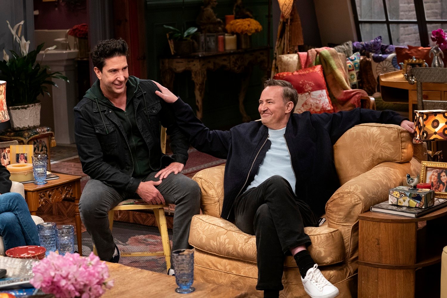 Matthew Perry and David Schwimmer sit in chairs on the Friends set