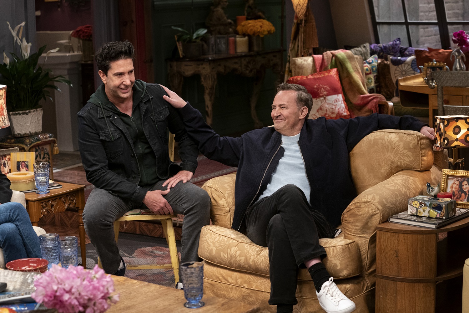 Matthew Perry and David Schwimmer sit in chairs on the Friends set