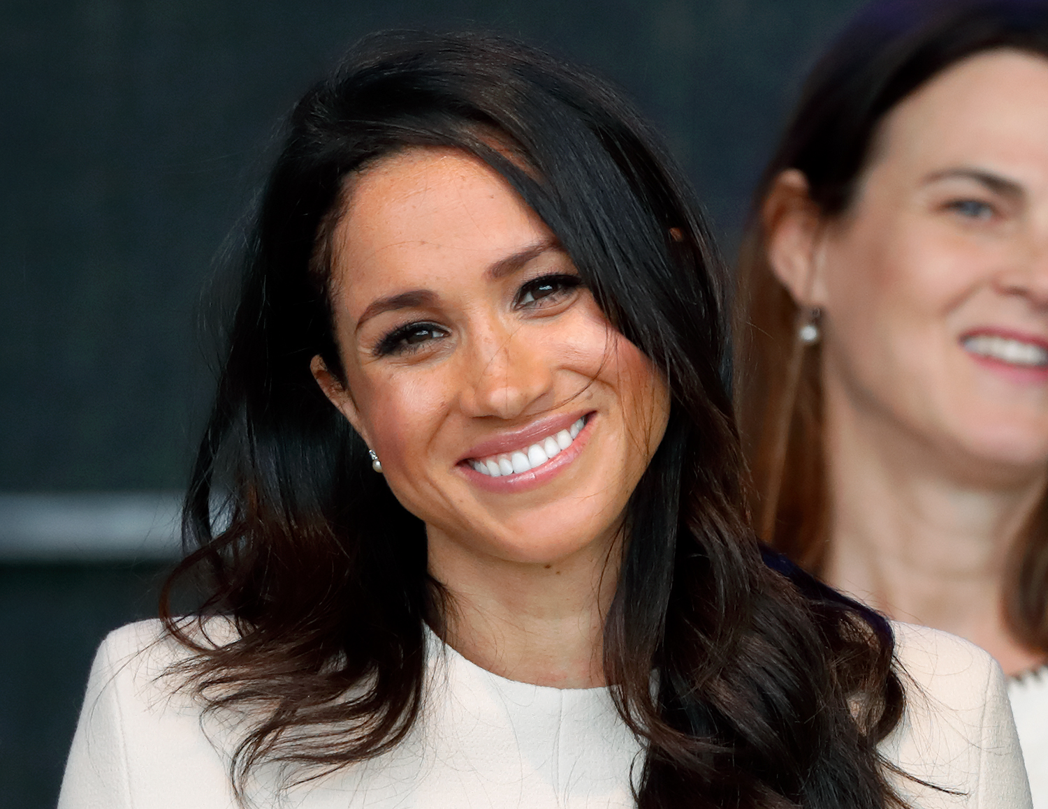Photo of Meghan Markle from the shoulders up with her hair down and smiling for a photo