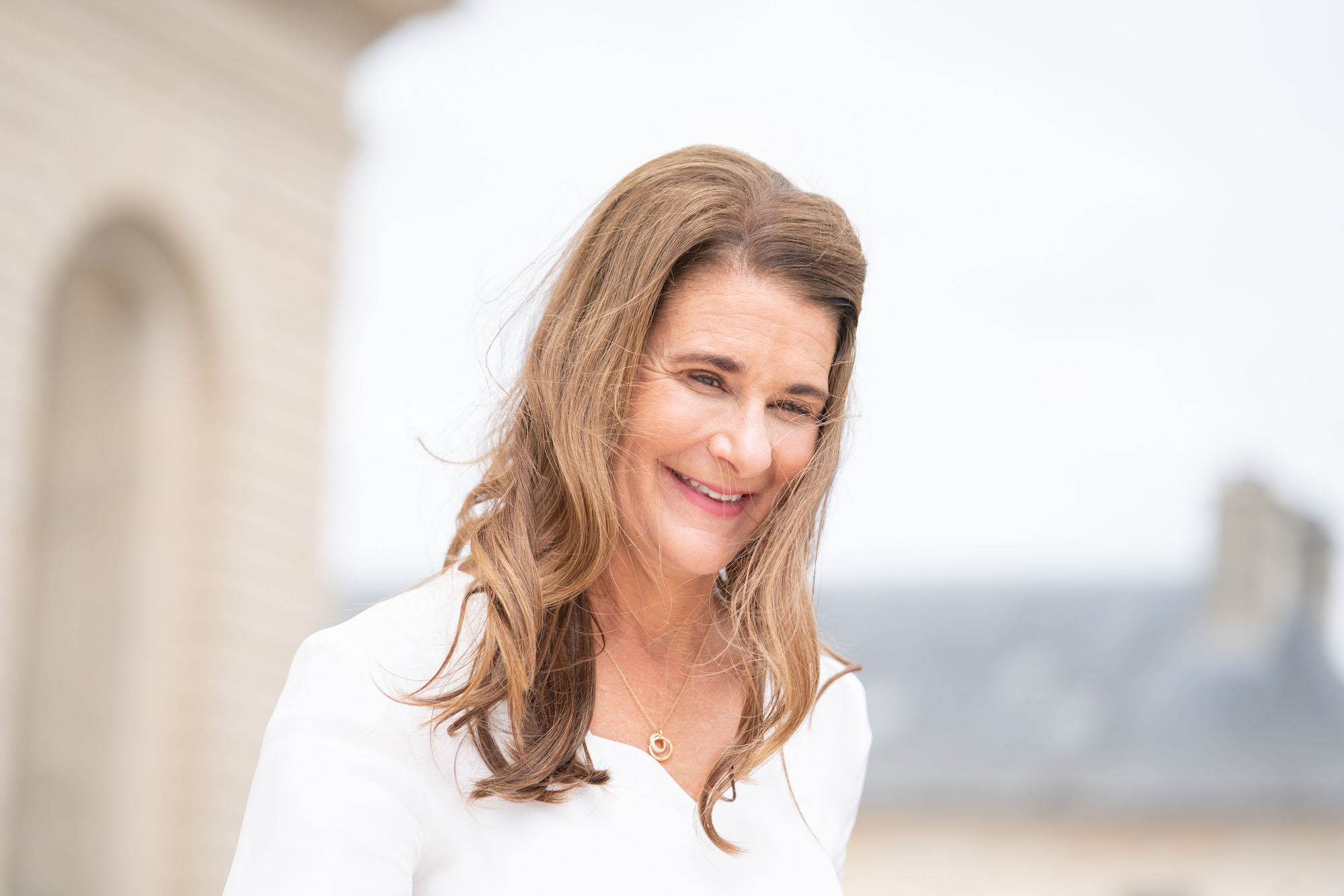 Melinda Gates, Bill Gates' wife, smiling outdoors while wearing white 