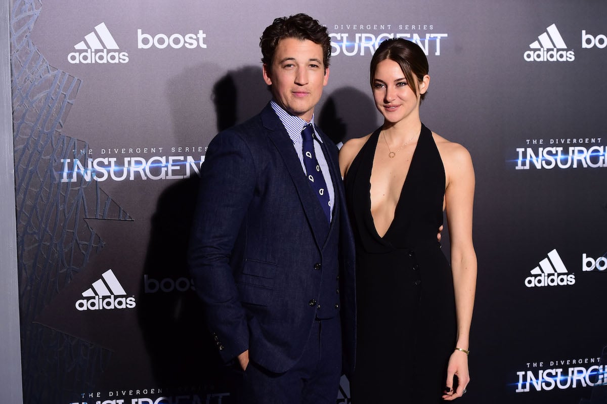 Miles Teller wears a blue suit as he poses with Shailene Woodley, who is wearing a black dress.