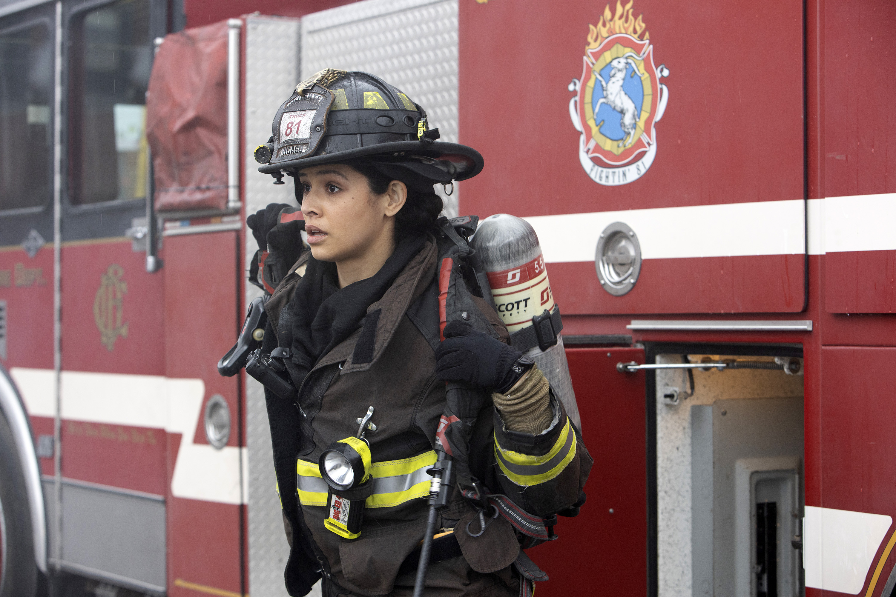 Miranda Rae Mayo as Stella Kidd on 'Chicago Fire' puts on her gear in front of a fire truck.