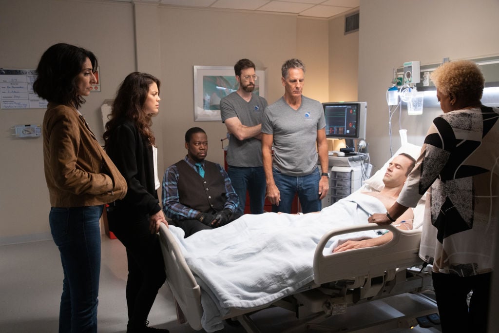 Necar Zadegan as Special Agent Hannah Khoury, Vanessa Ferlito as FBI Special Agent Tammy Gregorio, Daryl Chill Mitchell as Patton Plame, Rob Kerkovich as Forensic Scientist Sebastian Lund, Scott Bakula as Special Agent Dwayne Pride, and CCH Pounder as Dr. Loretta Wade stand over Christopher La Salle played by Lucas Black as he lies in a hospital bed, unconscious.