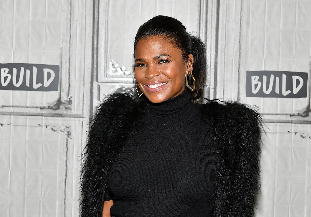 Nia Long smiles as she poses on the red carpet in a black feathered outfit