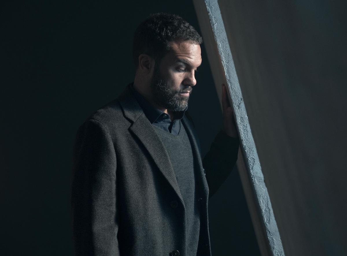 O-T Fagbenle looks somber while looking down in a grey suit in a dark room in 'The Handmaid's Tale' Season 4
