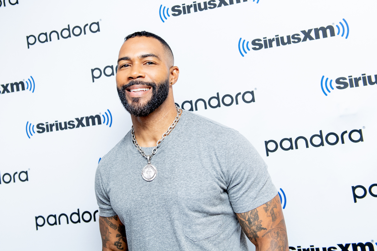 Omari Hardwick smiles wearing a grey t-shirt