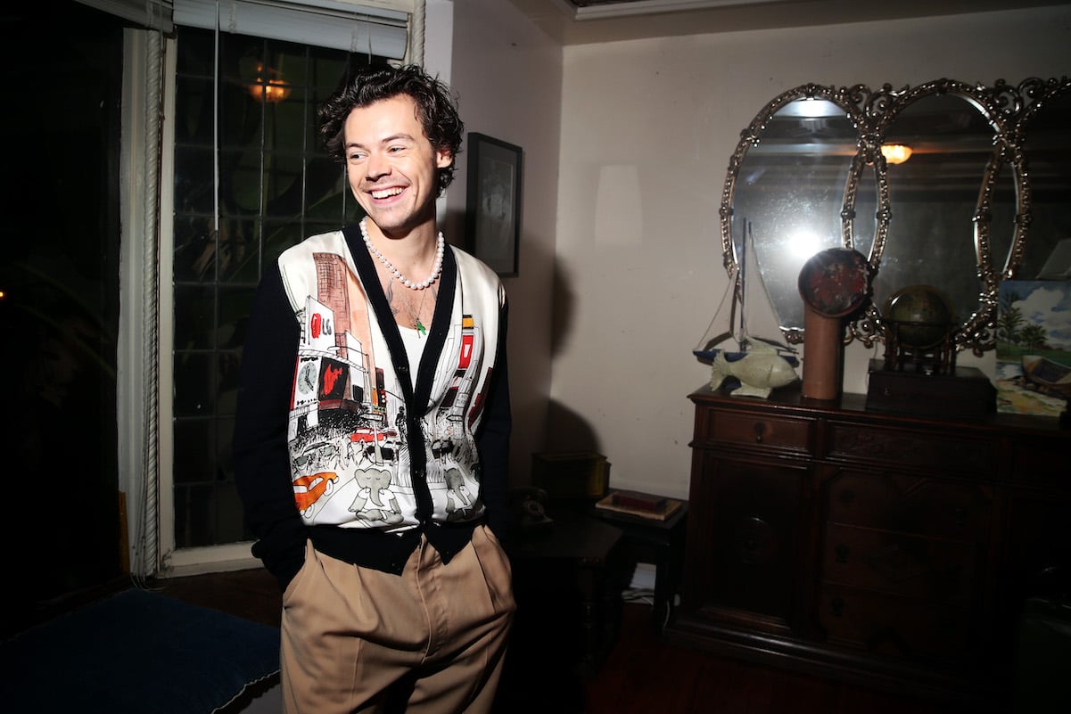 Harry Styles from One Direction in a cardigan and beige pants