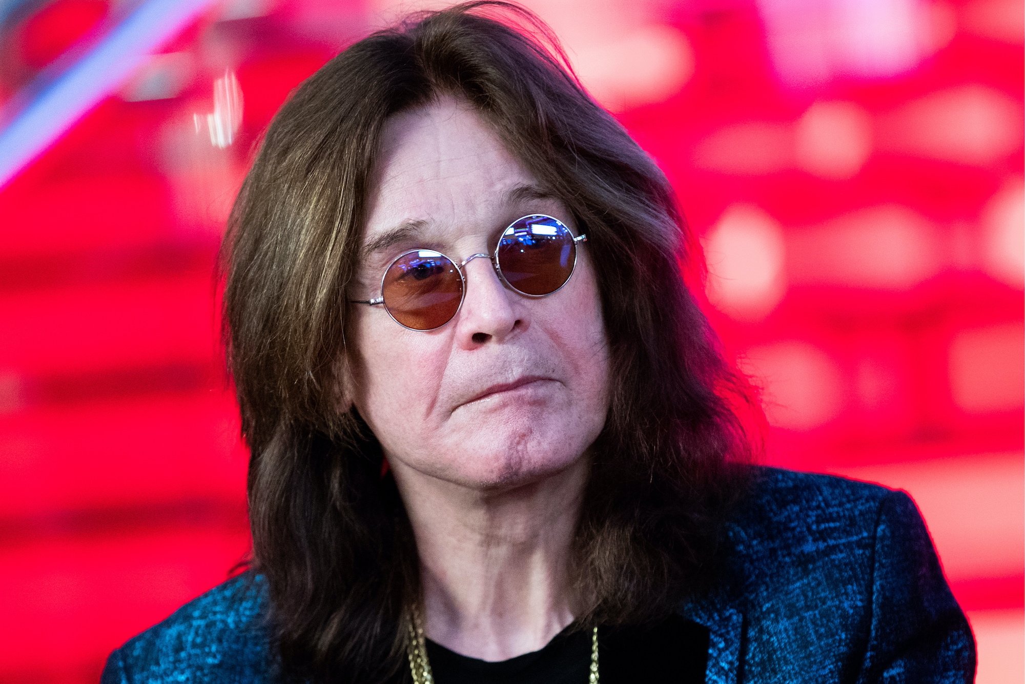 Ozzy Osbourne in front of a red background