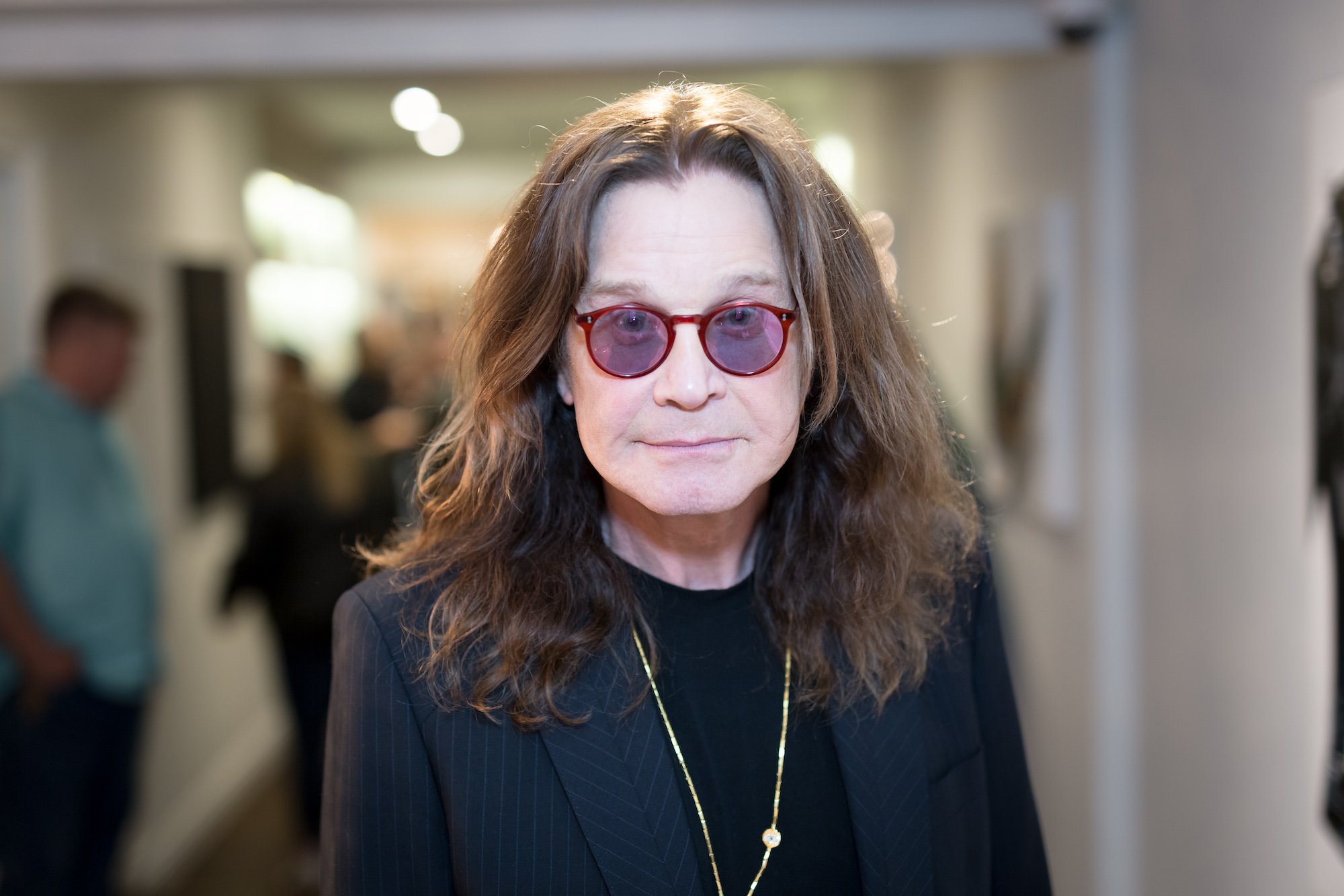 Ozzy Osbourne smiling in front of a blurred background