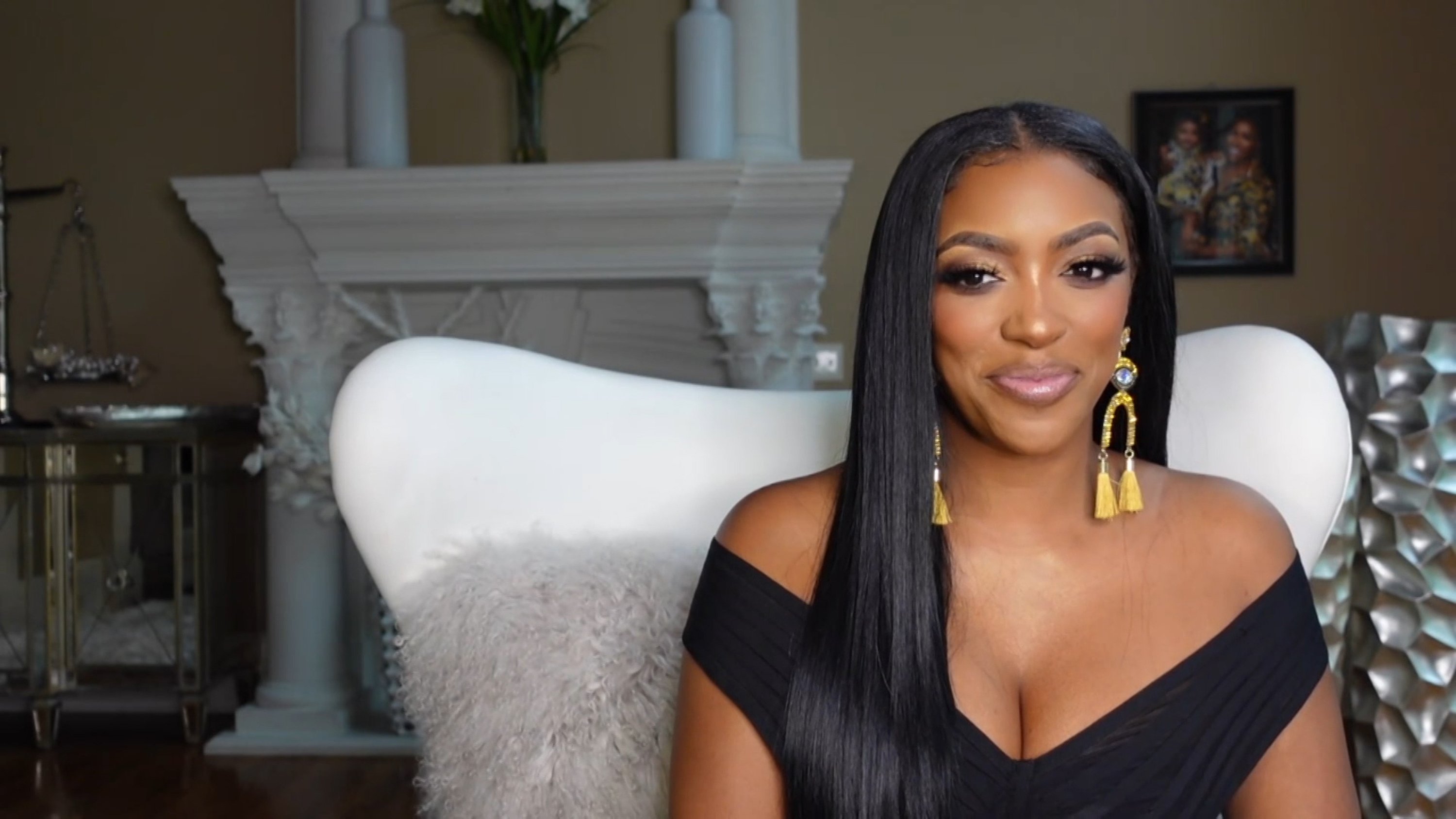 Porsha Williams of 'RHOA' smiling while wearing a black dress and yellow earrings on 'Watch What Happens Live with Andy Cohen'