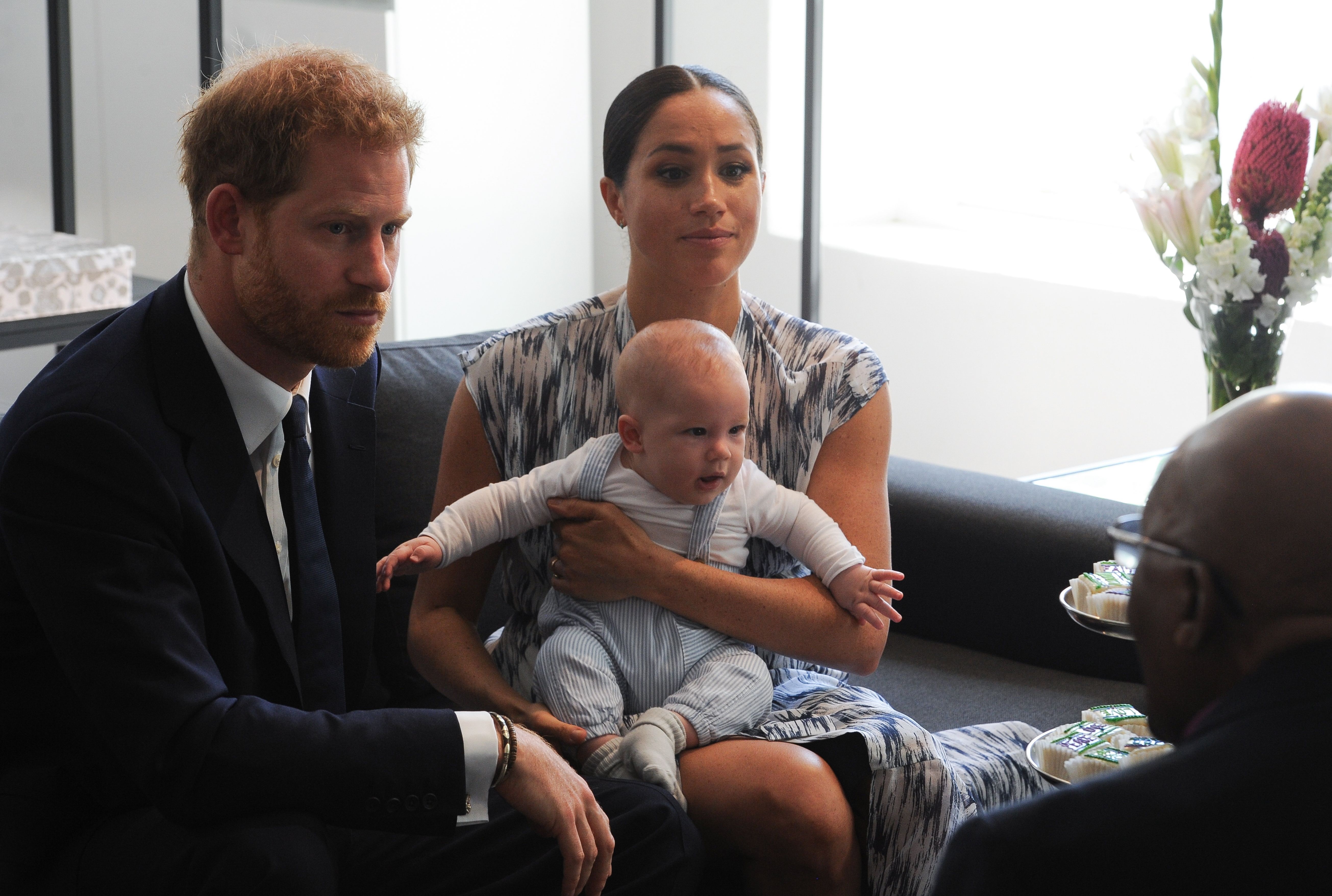 Prince Harry and Meghan Markle holding their son, Archie, on her lap during a meeting with Archbishop Desmond Tutu in Cape Town