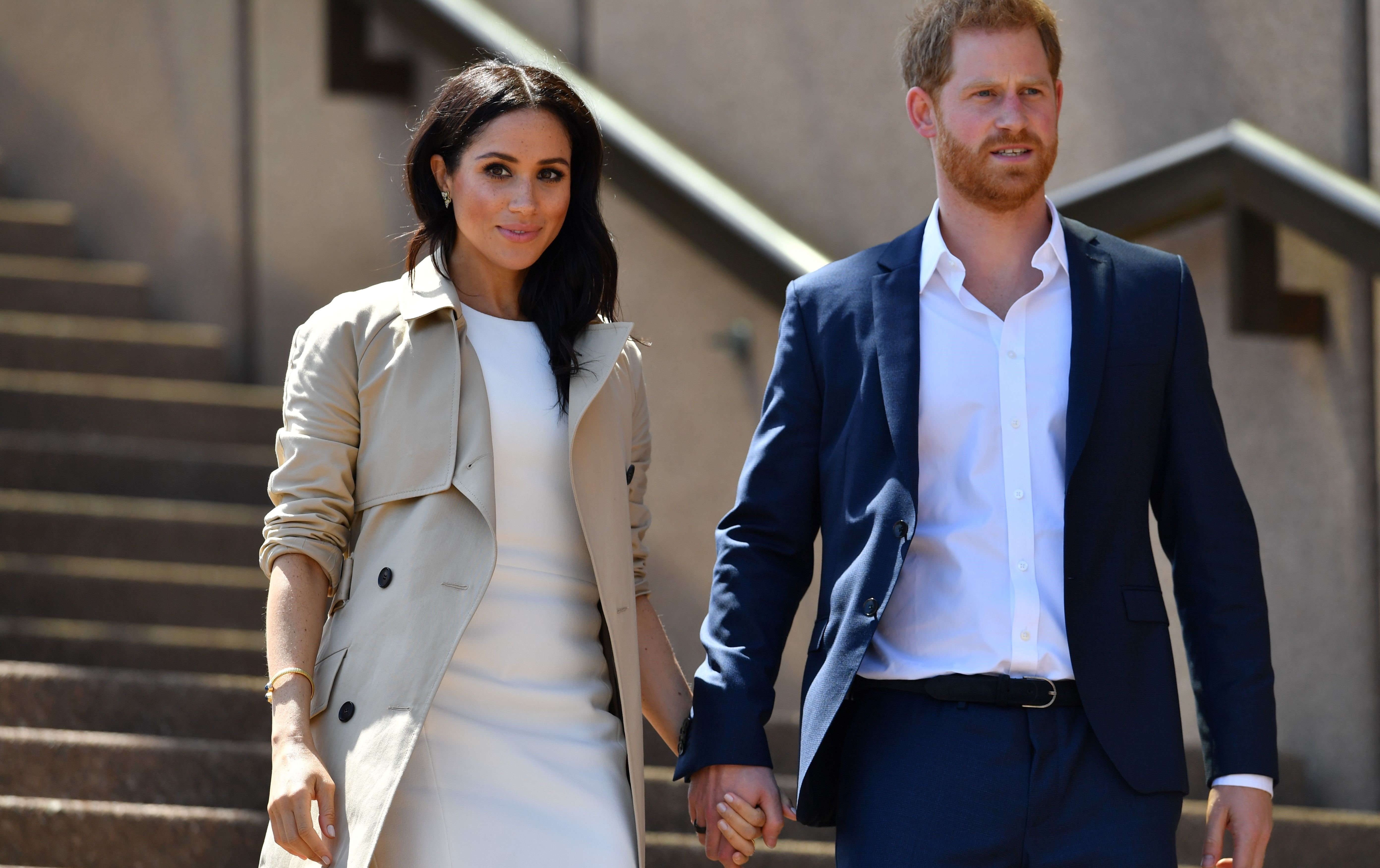 Prince Harry and Meghan Markle walk down the stairs of Sydney's Opera House to meet people