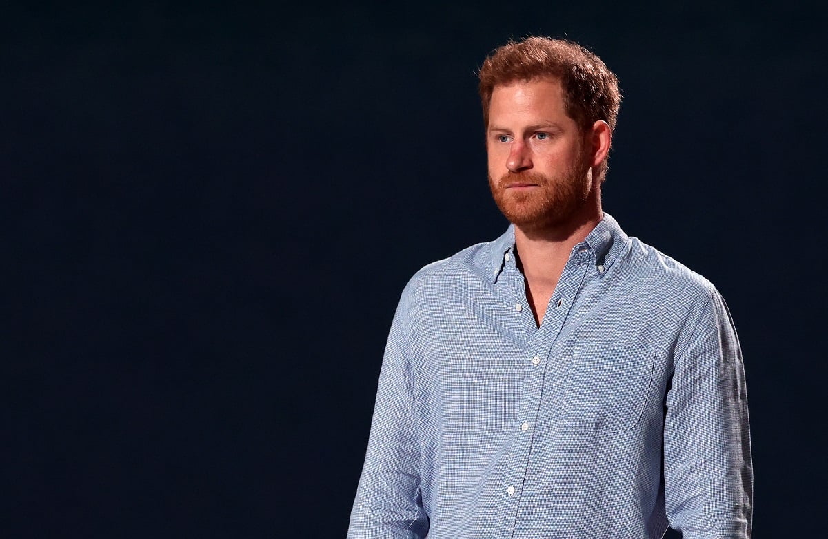 Prince Harry in a light blue shirt against a dark background