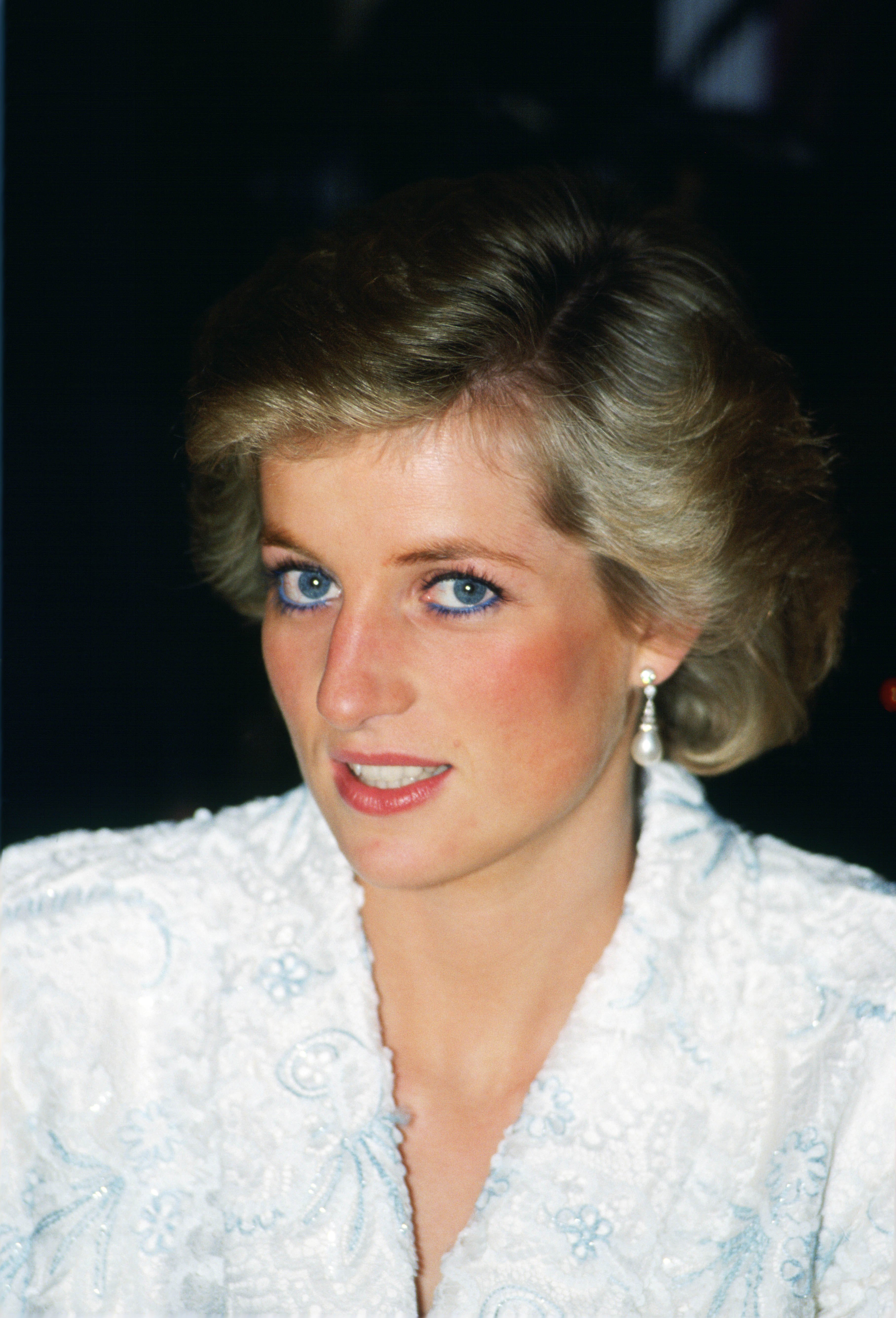 Princess Diana wearing blue eyeliner and a white and blue lace and sequin evening coat