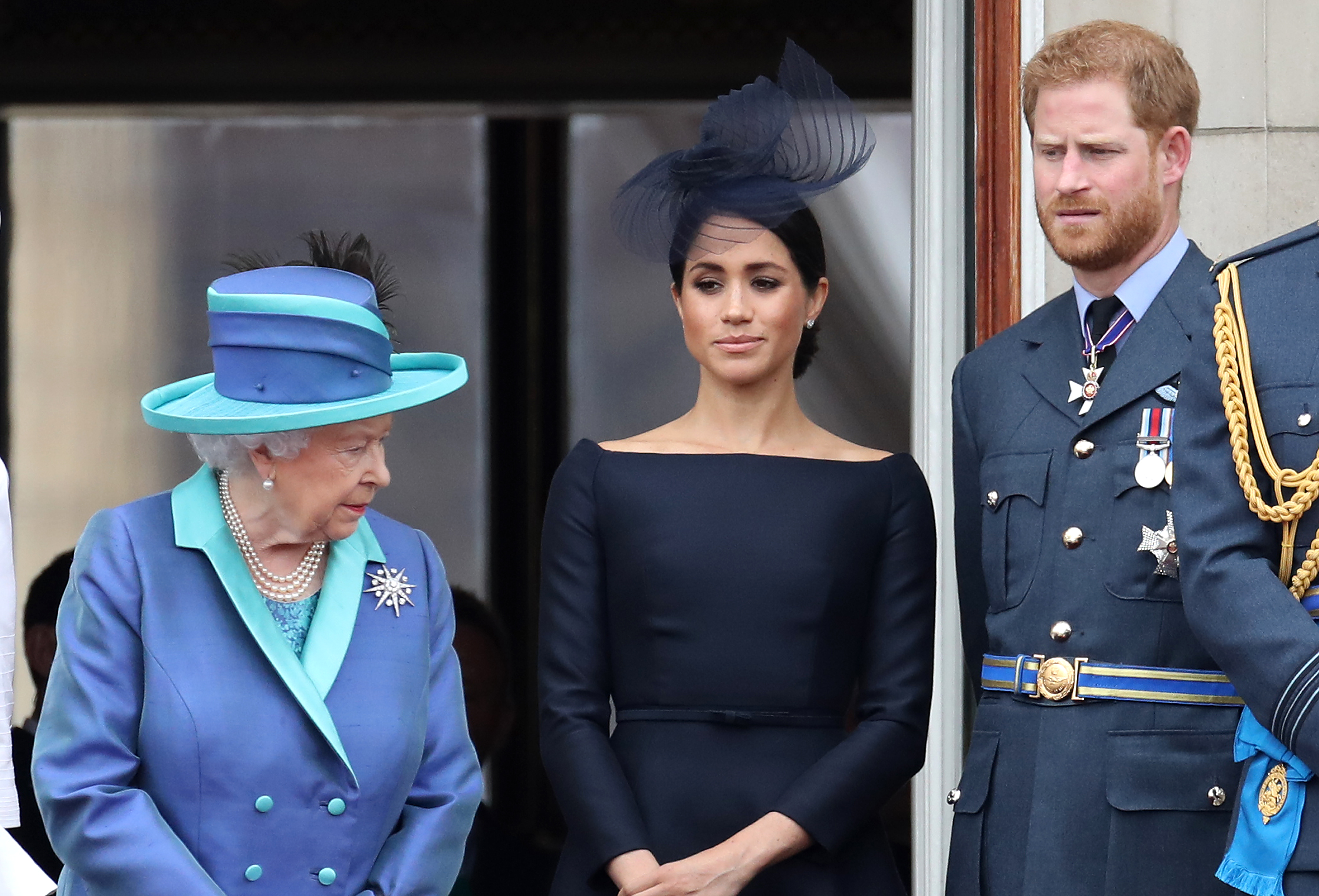Queen Elizabeth II, Prince Harry, and Meghan Markle standing on the balcony of Buckingham Palace