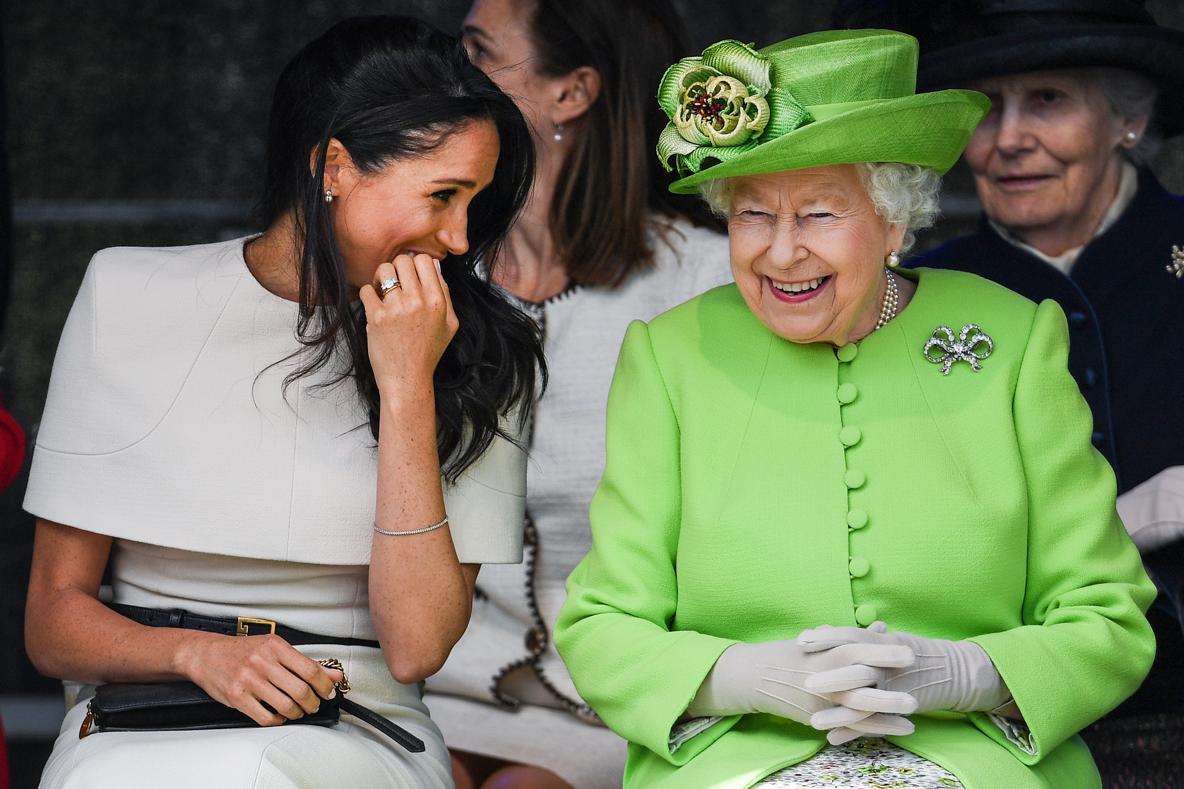 Queen Elizabeth II and Meghan Markle sitting together and laughing during a ceremony to open the Mersey Gateway Bridge in England in 2018