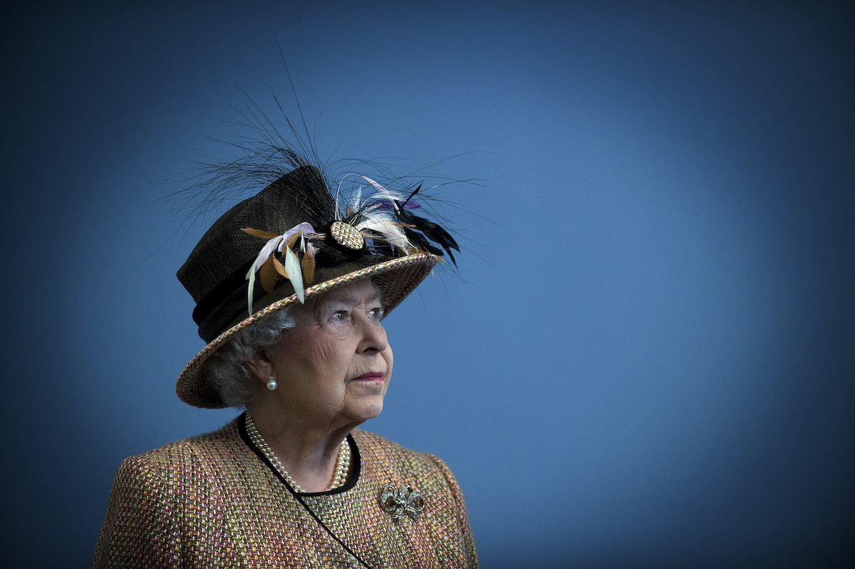 Queen Elizabeth looks to the side wearing a large hat