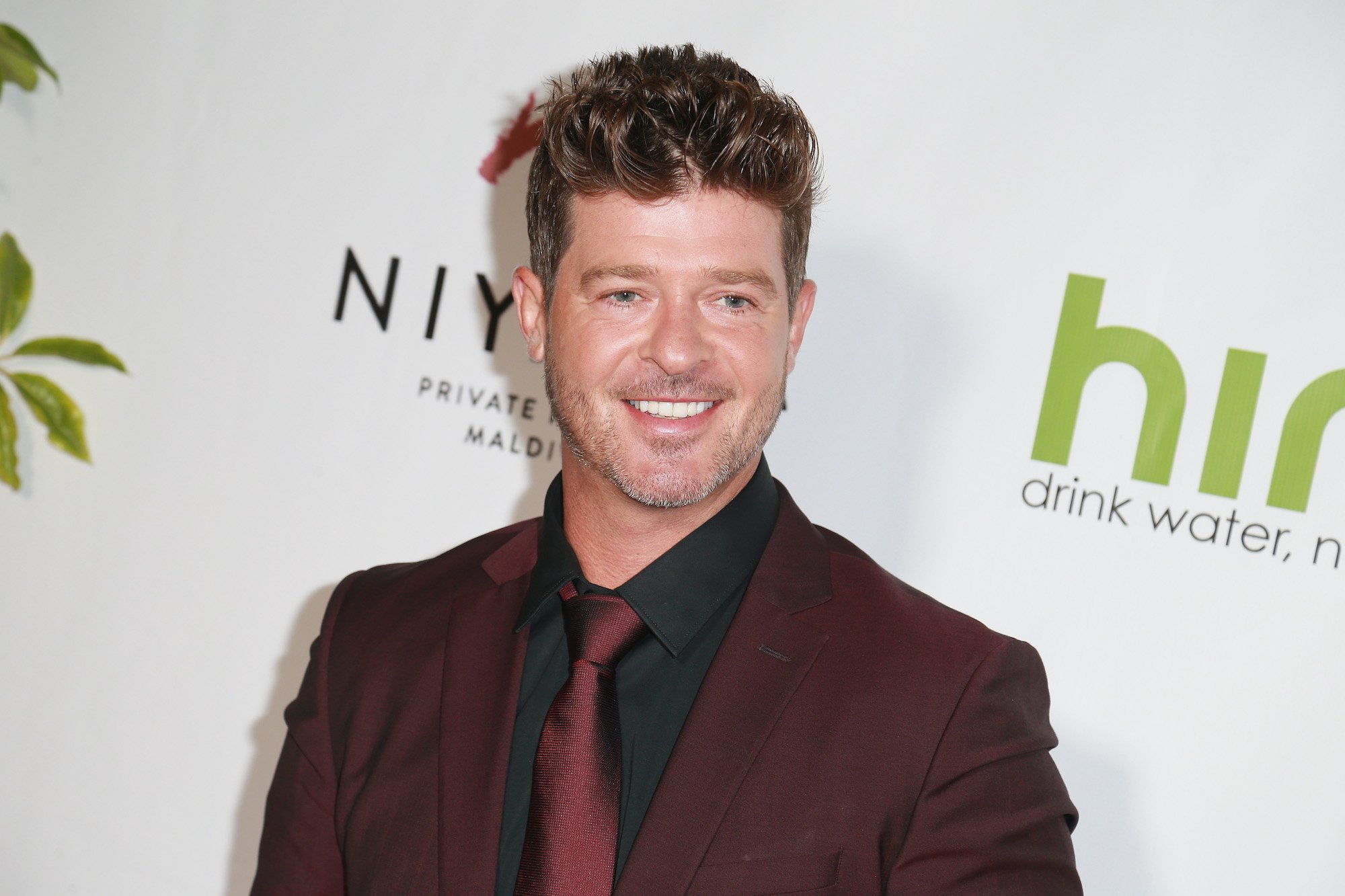 Robin Thicke smiling in front of a white background