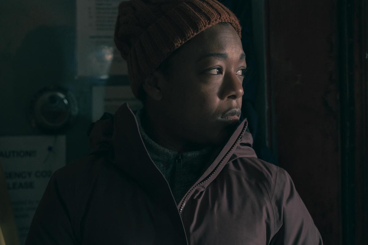 Samira Wiley in a brown coat and beanie looking out a window on a boat in 'The Handmaid's Tale' Season 4