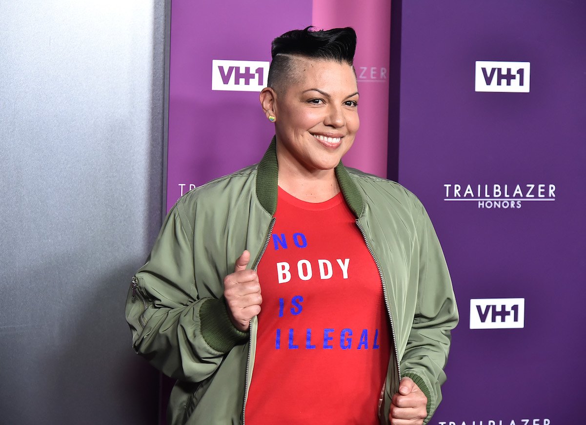 Sara Ramirez in a 'No Body is Illegal' t-shirt and green jacket