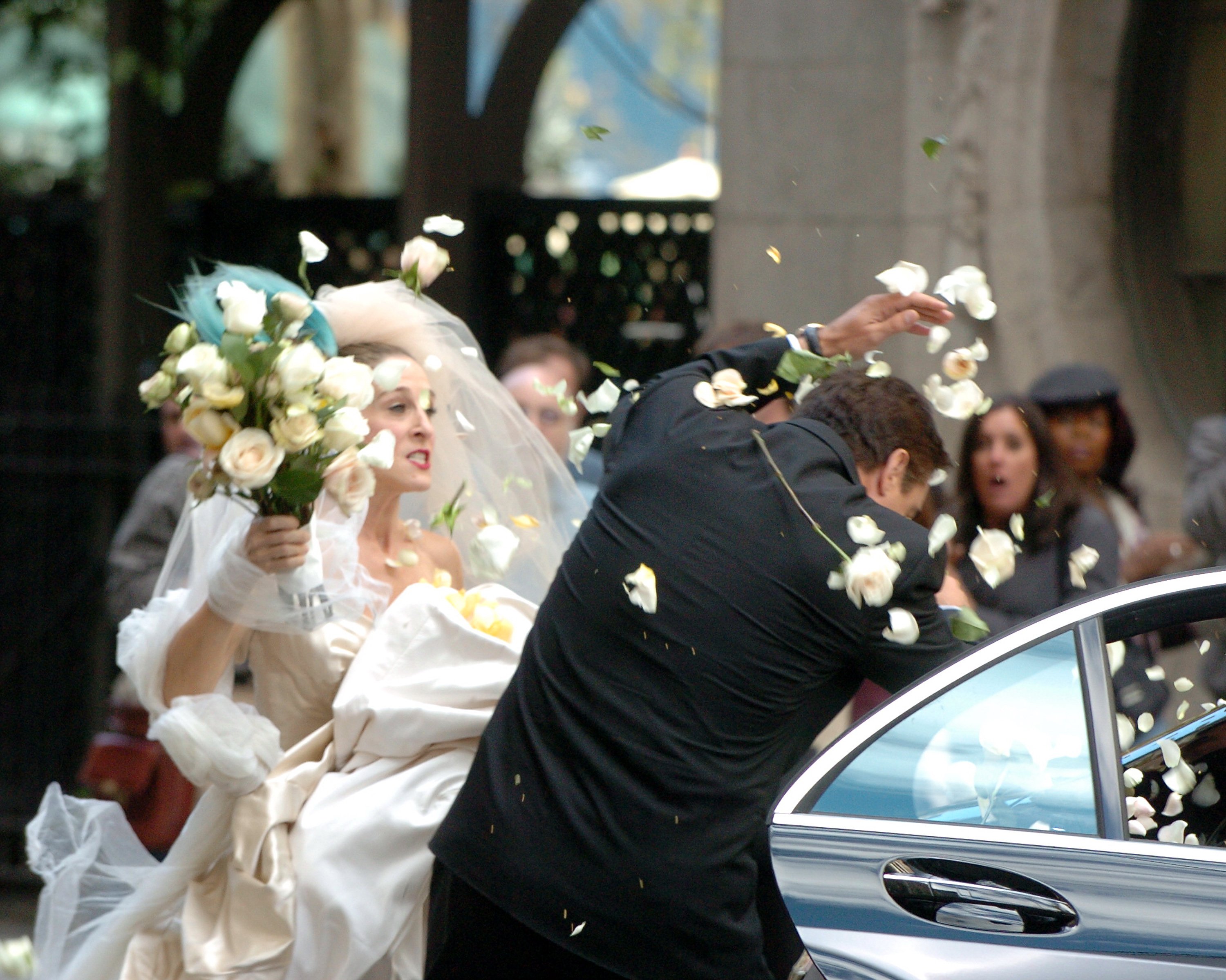 Sarah Jessica Parker wearing a Vivienne Westwood dress as Carrie Bradshaw while hitting Chris Noth as Mr. Big with flowers.