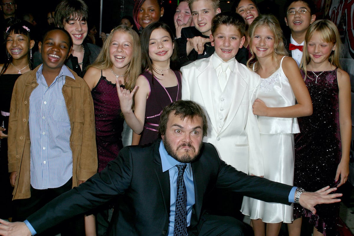 Jack Black poses wildly with his arms outstretched in front of the child actor stars of 'School of Rock'