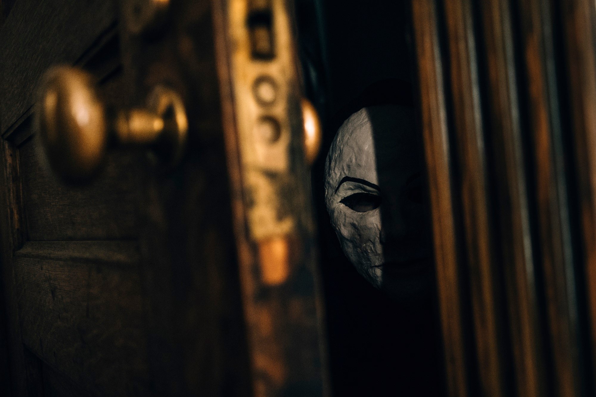 Seance mask peers through a crack in the door