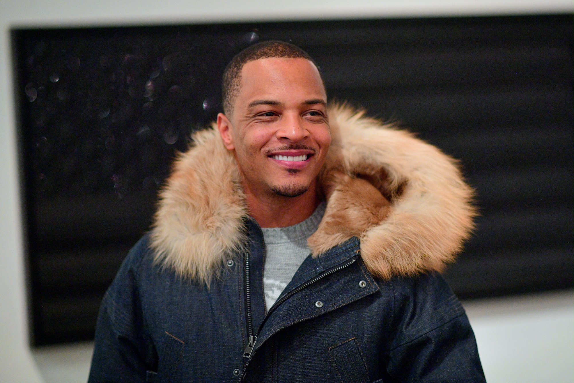 T.I. smiling, wearing a large fur lined hood