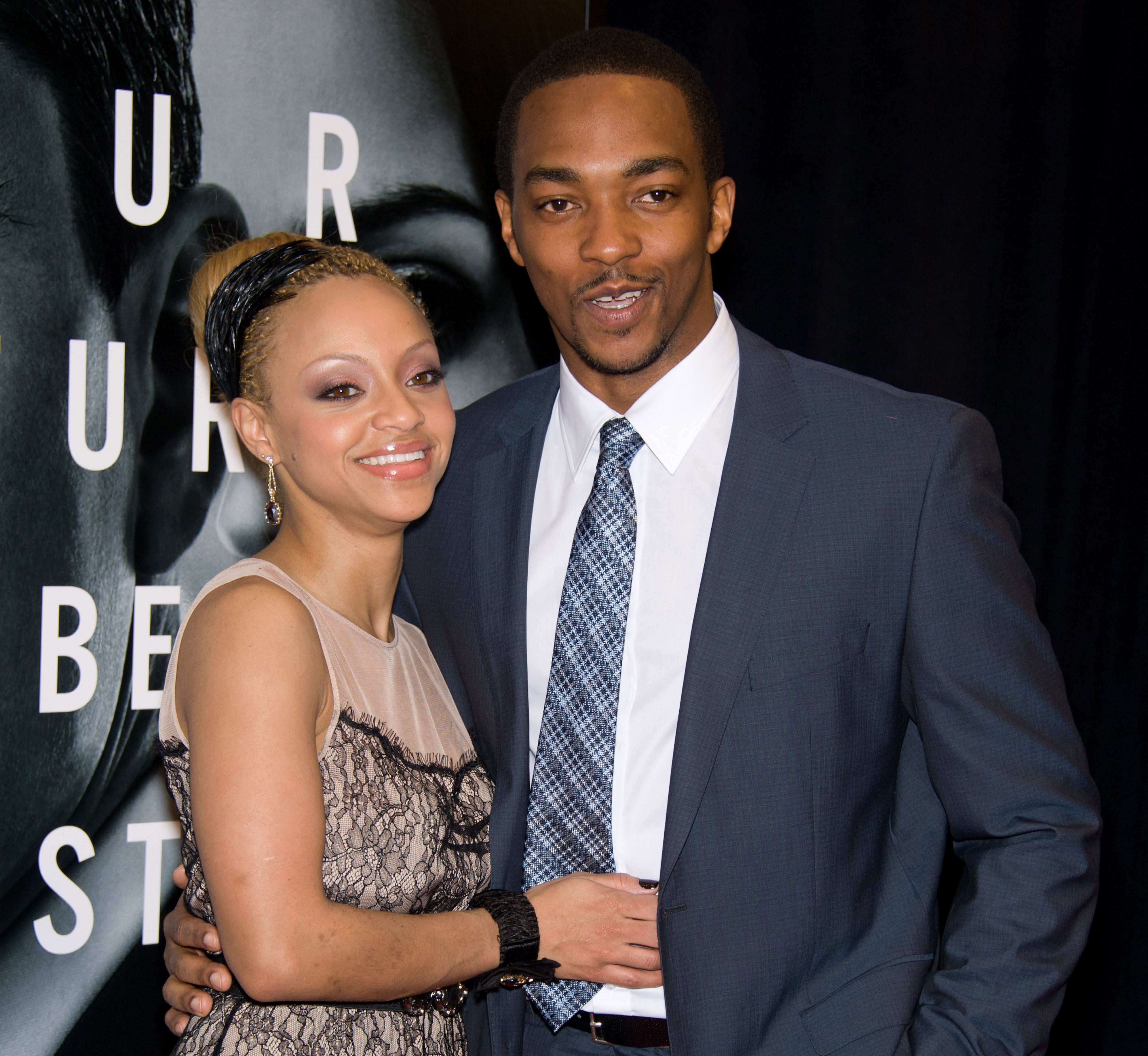 'The Falcon and the Winter Soldier' star Anthony Mackie wearing a blue suit and tie while embracing his ex-wife, Sheletta Capital. Capital is smiling while wearing a tan and black dress.