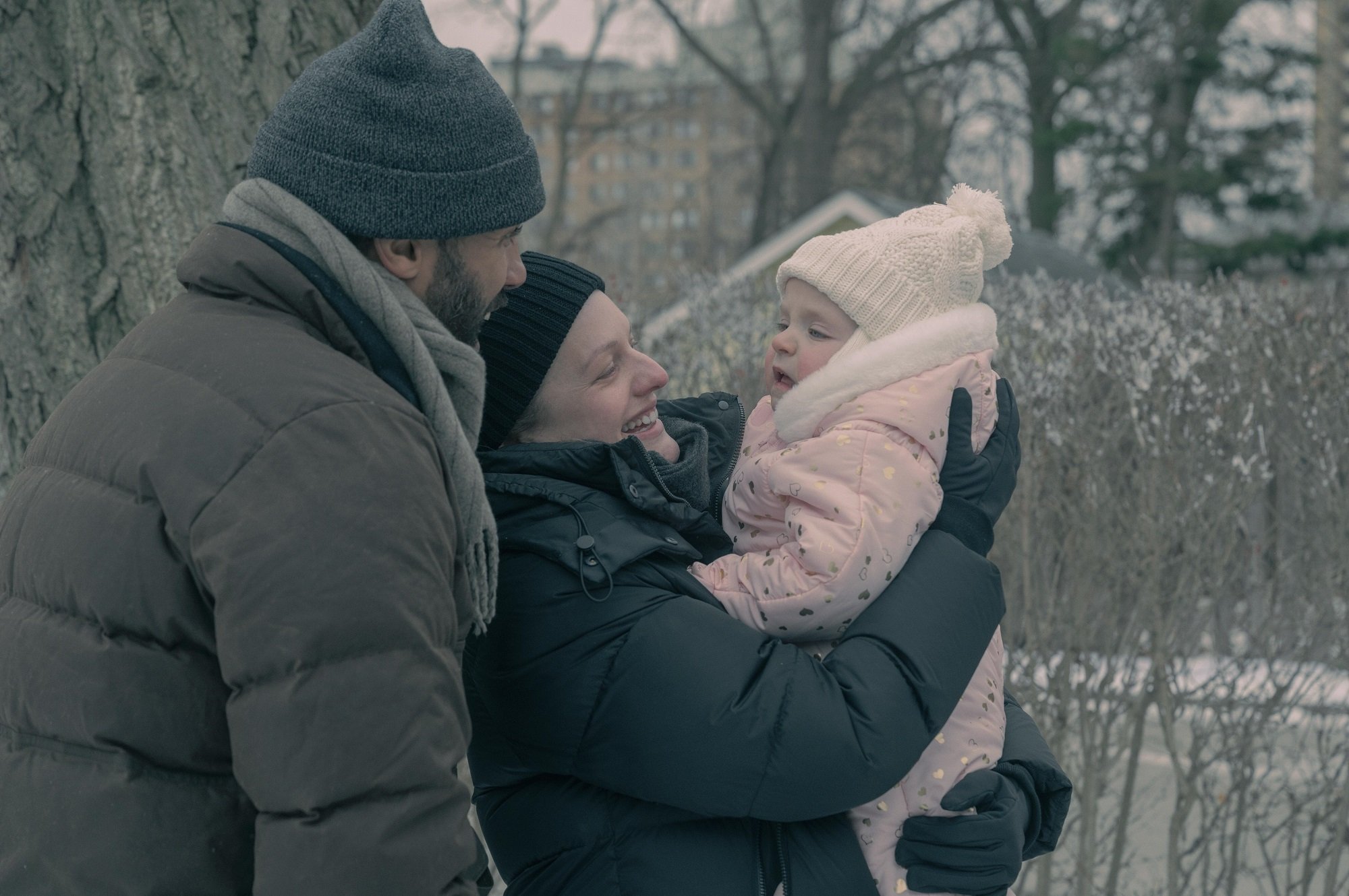 Luke (O-T Fagbenle) and June (Elisabeth Moss) play with Nichole in the snow in 'The Handmaid's Tale'