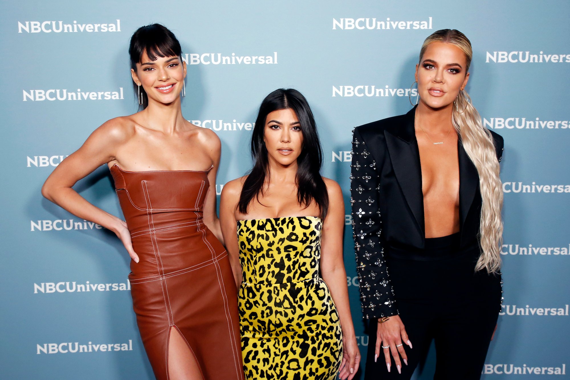 Kendall Jenner, Kourtney Kardashian, and Khloe Kardashian in front of a blue background