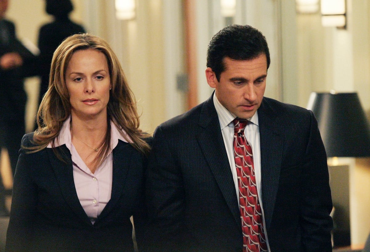 Melora Hardin as Jan Levinson and Steve Carell as Michael Scott walk together in a hallway wearing suits on 'The Office'