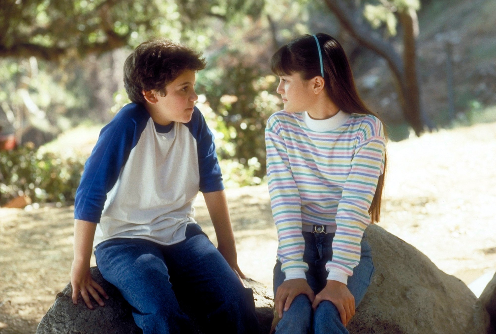 Fred Savage and Danica McKellar facing each other, sitting on rocks