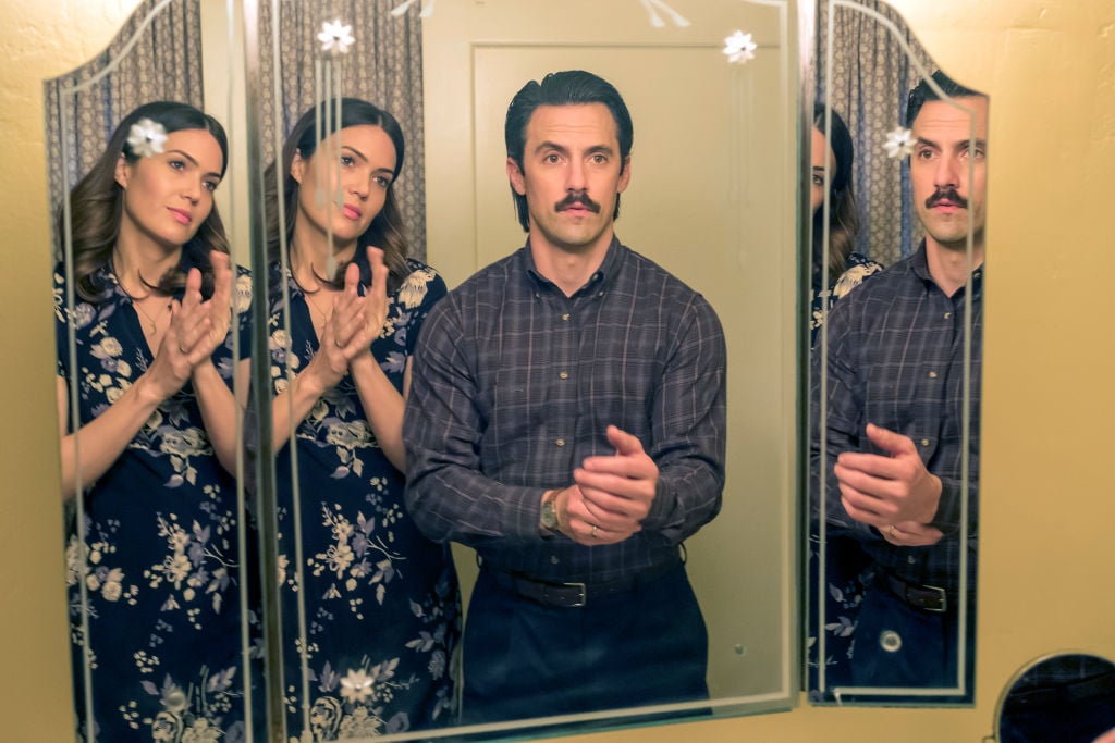 Mandy Moore as Rebecca looks at Milo Ventimiglia as Jack in the mnirror as they both get dressed to go out.