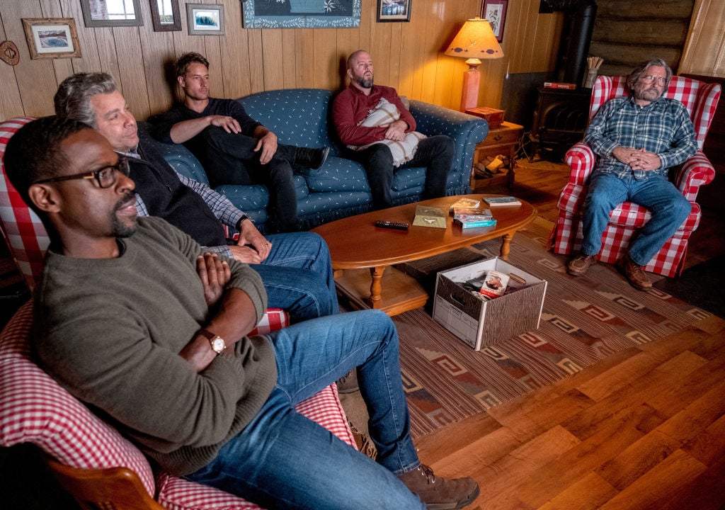 Sterling K. Brown as Randall, Jon Huertas as Miguel, Justin Hartley as Kevin, Chris Sullivan as Toby, Griffin Dunne as Nicky sit on a couch in the cabin watching TV on season 5 of 'This Is Us'.