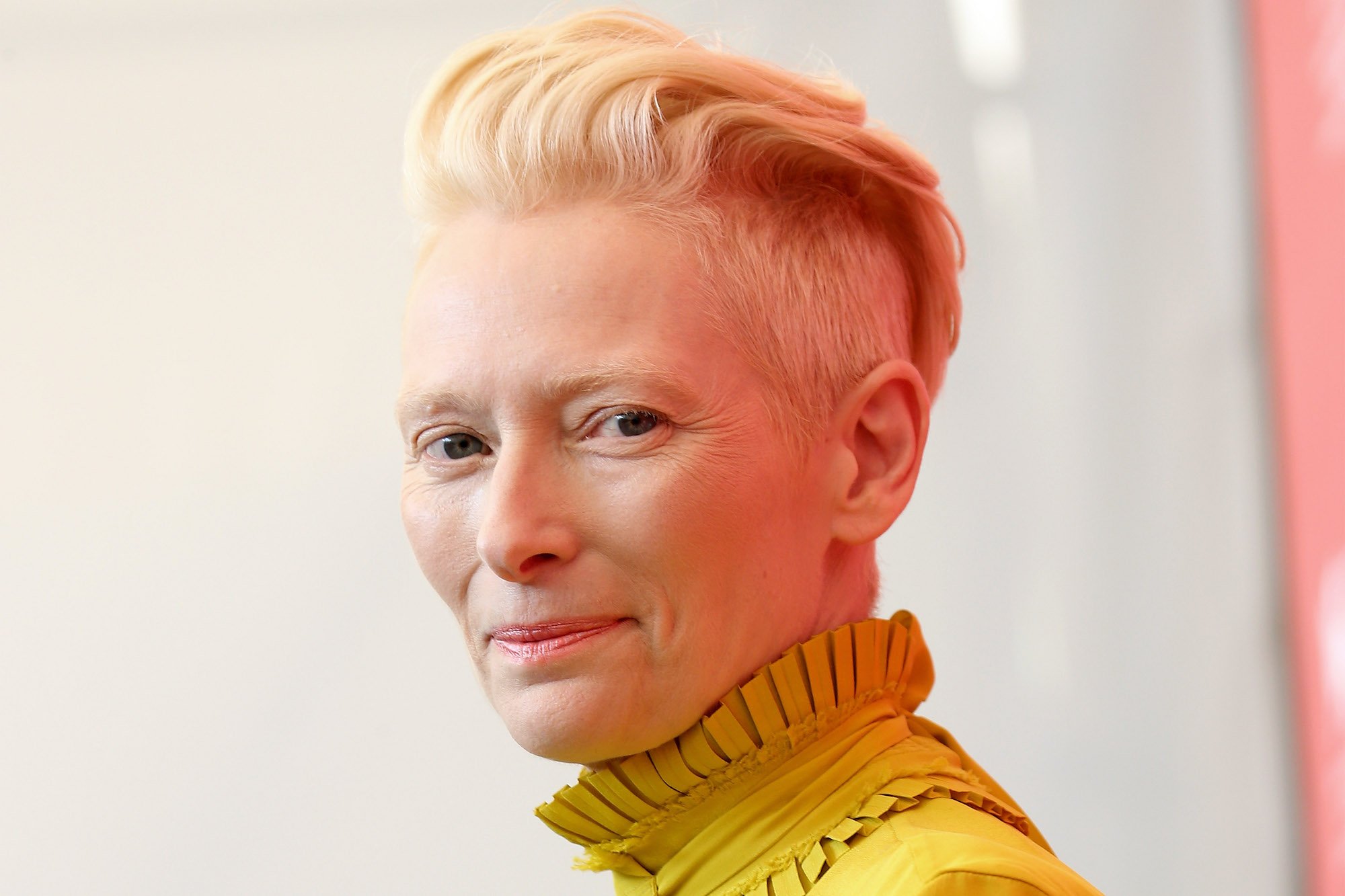 Tilda Swinton smiling in front of a white background