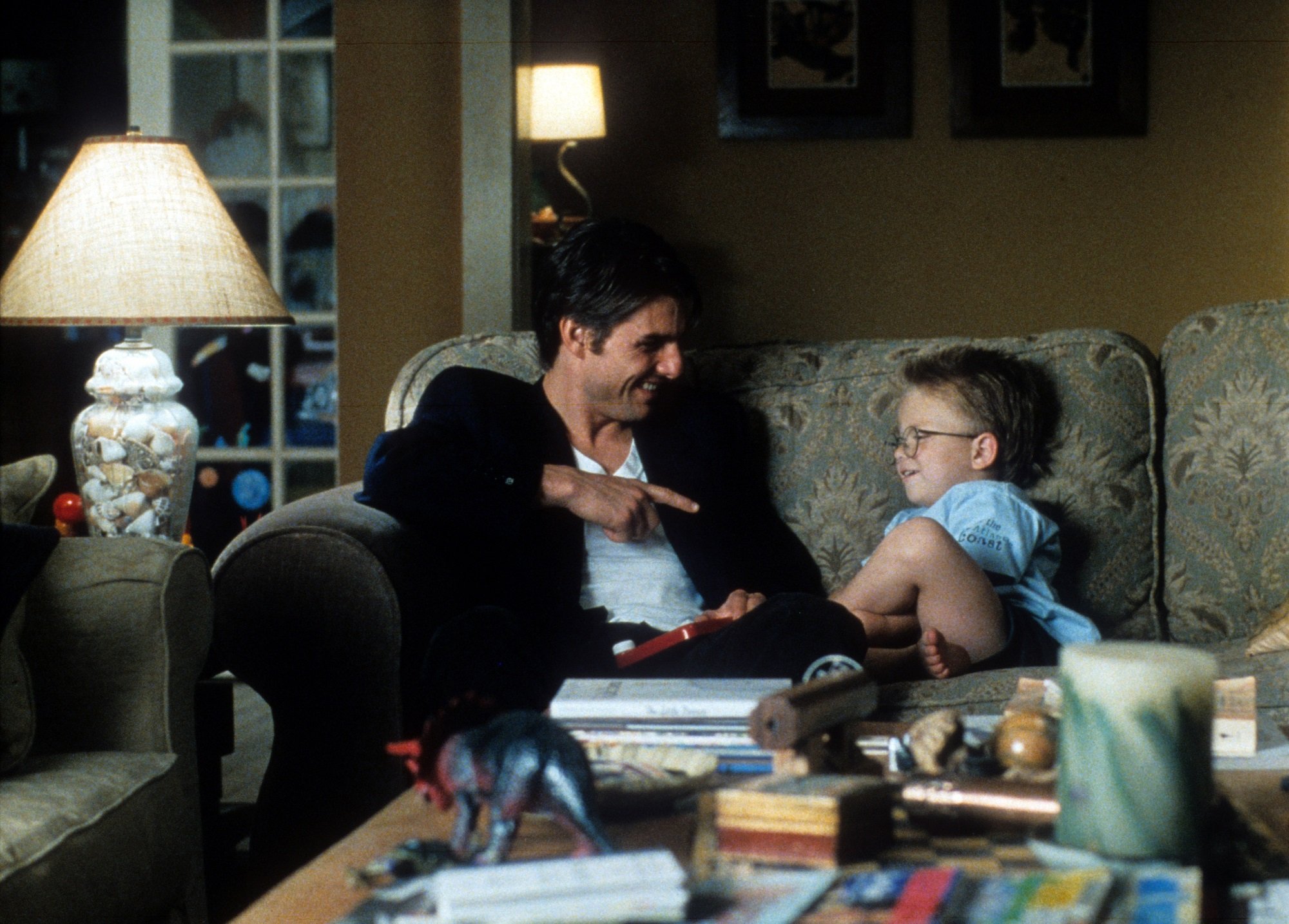 Tom Cruise sits on a sofa with Jonathan Lipnicki in Jerry Maguire