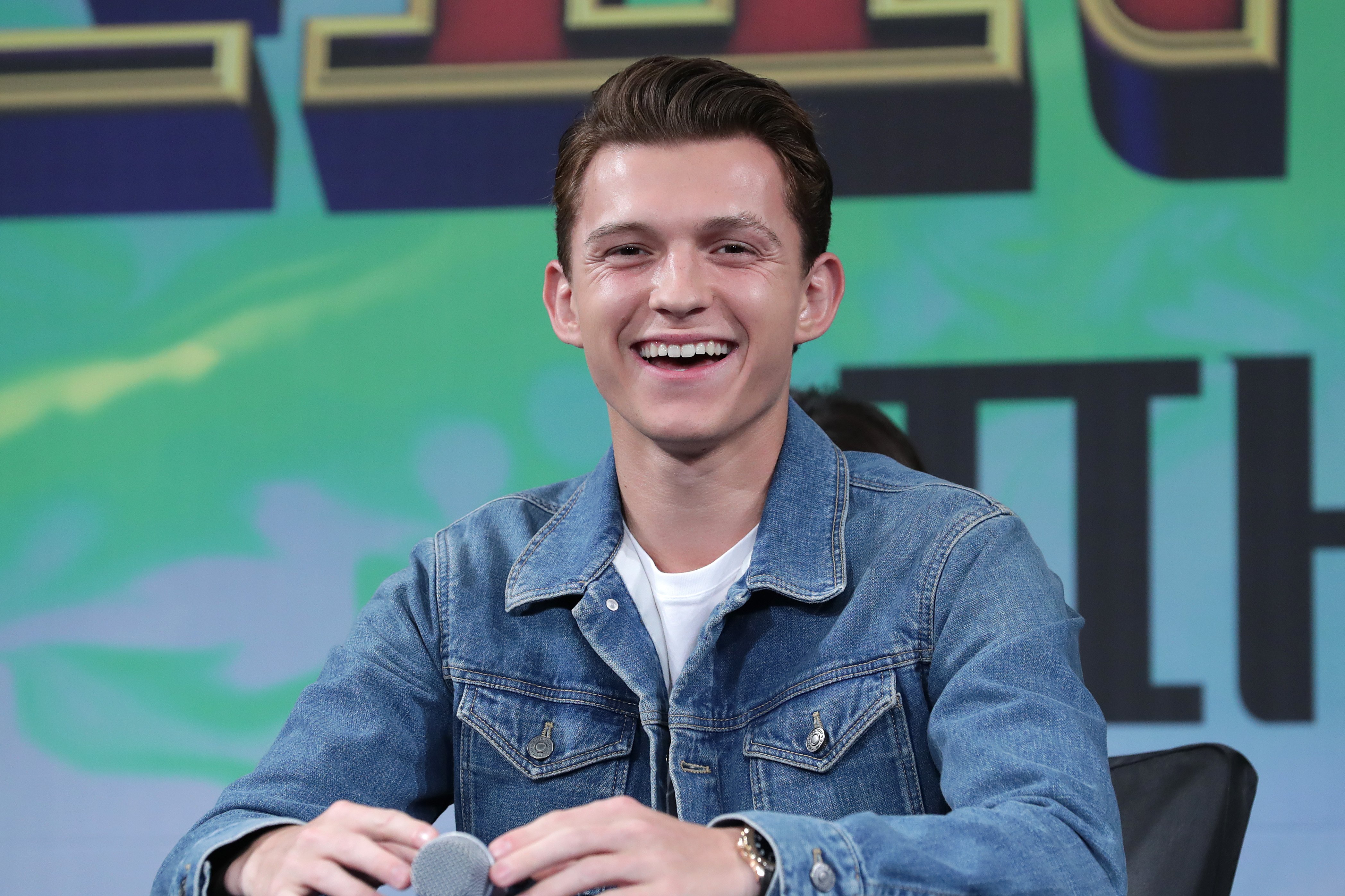 Actor Tom Holland attends the press conference for 'Spider-Man: Far From Home' smiling, seated at a table