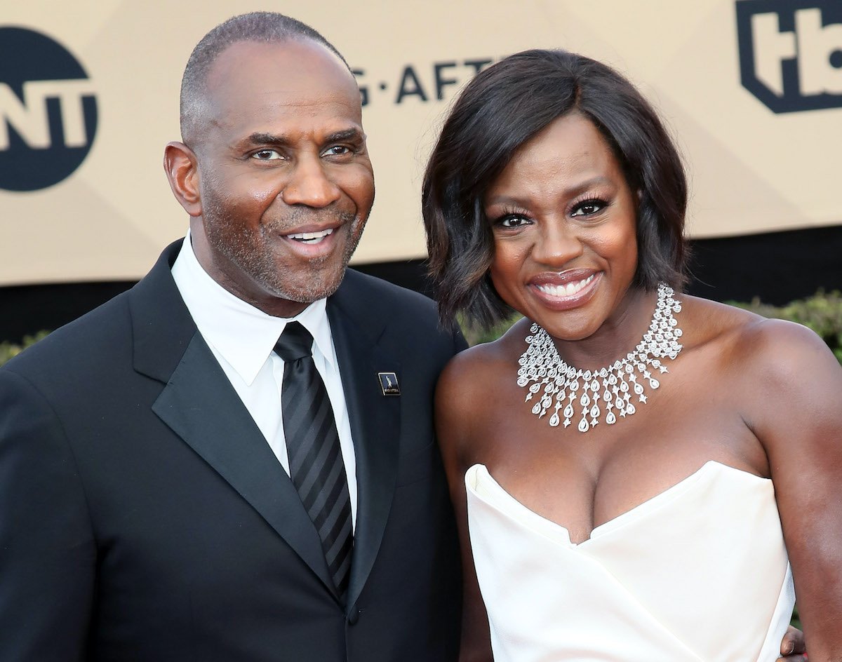 Viola Davis smiles in a white gown and diamond necklace while posing with husband Julius Tennon in a black suit at the SAG Awards