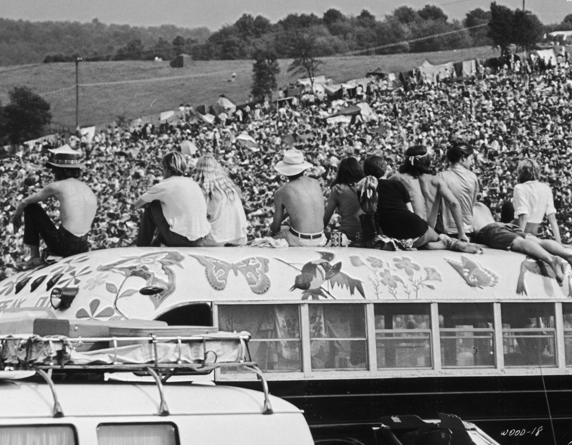Fans sitting on top of a painted bus at the Woodstock Music Festival, 1969