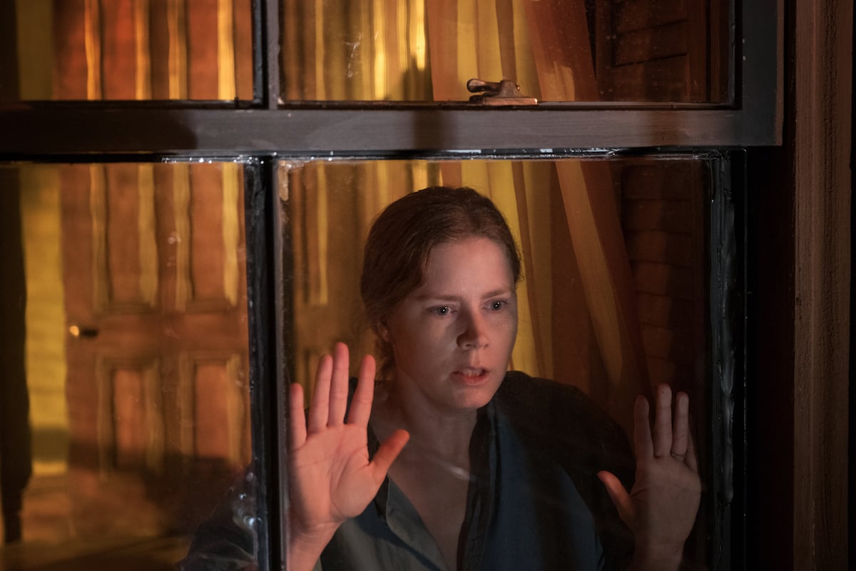 Amy Adams looking out window with hands against the glass in The Woman in the Window